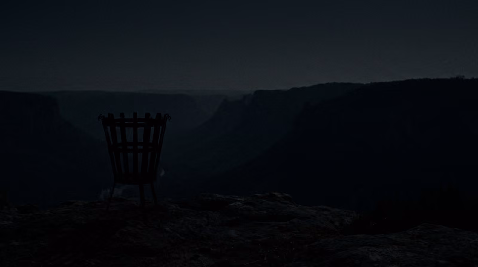 An unlit iron beacon on a canyon rim over a vast dark valley at night.